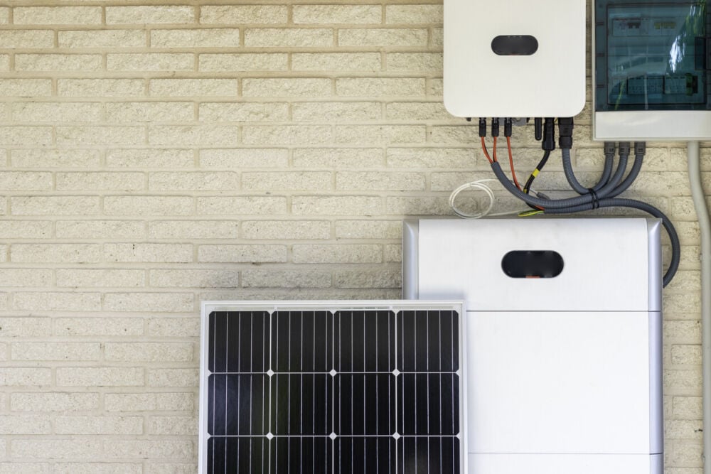 Front view of photovoltaic panel and battery installation leaning on the beige white wall with no people. Renewable energy concept.