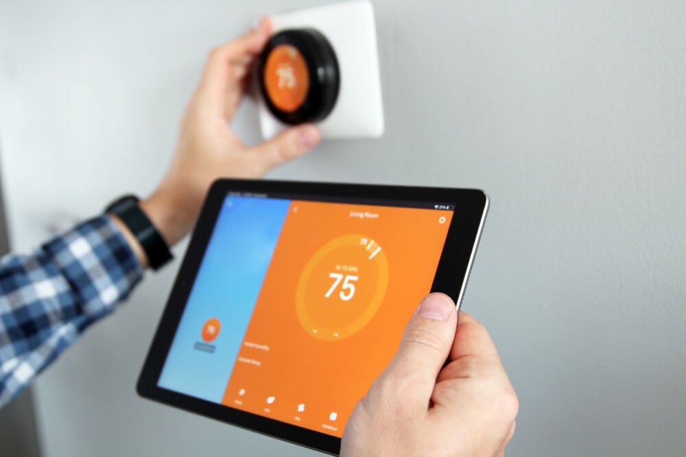 Man is Adjusting temperature using a tablet with smart home app in modern living room.