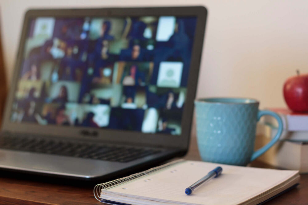 a laptop open on a desk with a mug and notebook next to it